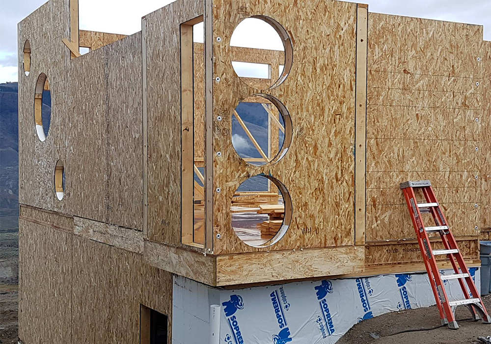 Exterior image of a house under construction with holes in the wall for window installation