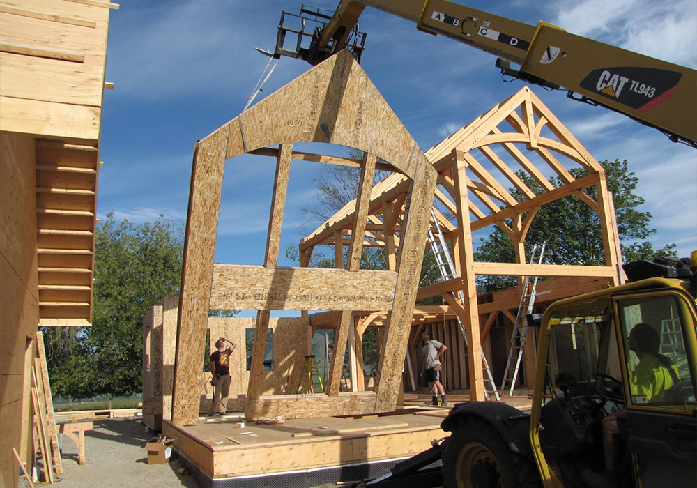 A crane lifting an exterior wall for a house under construction