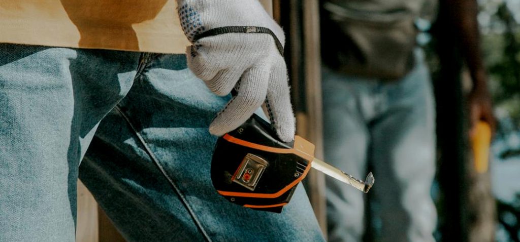 Man holding a tape measure wearing a glove