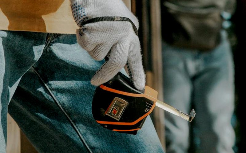 Man holding a tape measure wearing a glove